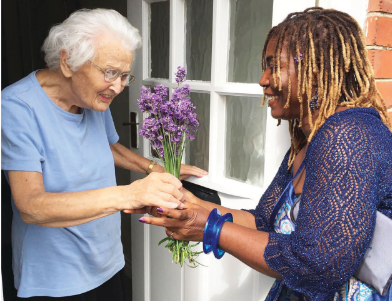 Image of a lady giving an elderly woman a bouquet of flowers